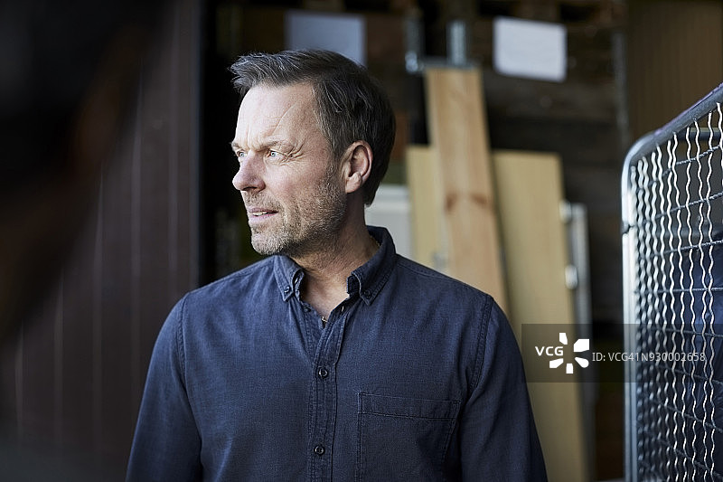 仓库里，站在同事面前向远处看的年长的男工人图片素材