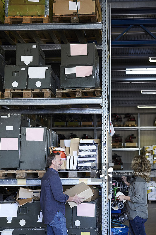 微笑的男志愿者和女同事在仓库货架旁图片素材