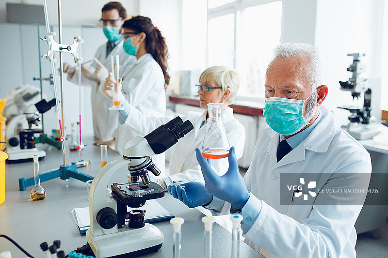 在实验室研究液体的资深男科学家图片素材