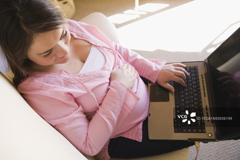 孕妇在沙发上使用笔记本电脑图片素材