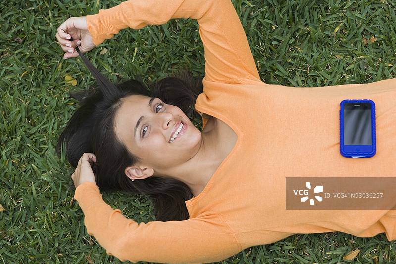 青少年女孩躺在公园里玩手机图片素材