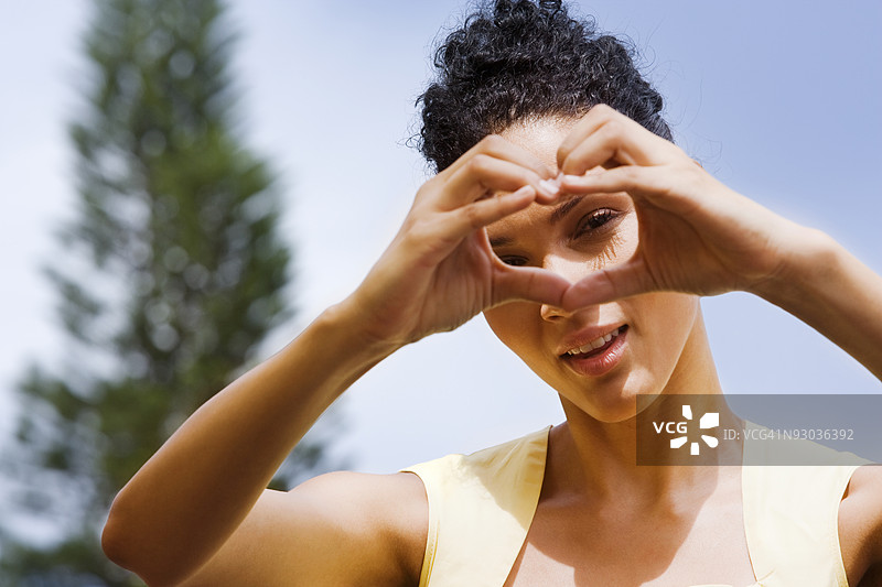 女人在脸前用手做心形手势图片素材