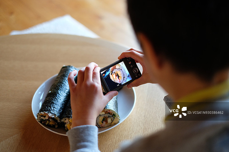 男孩正在拍摄寿司照片图片素材