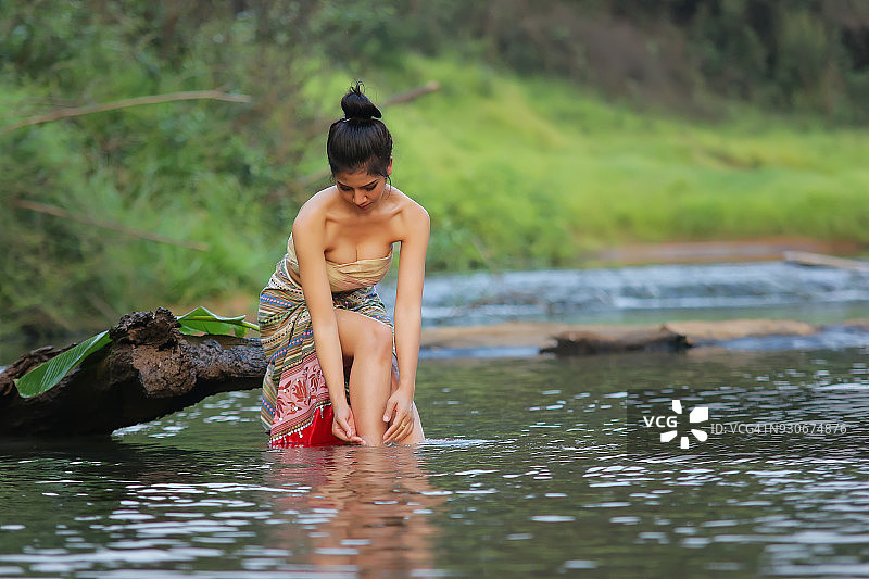 穿着纱笼在河里洗澡的亚洲女孩图片素材