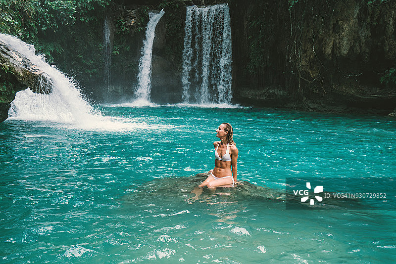 年轻女人凝视着美丽的瀑布图片素材