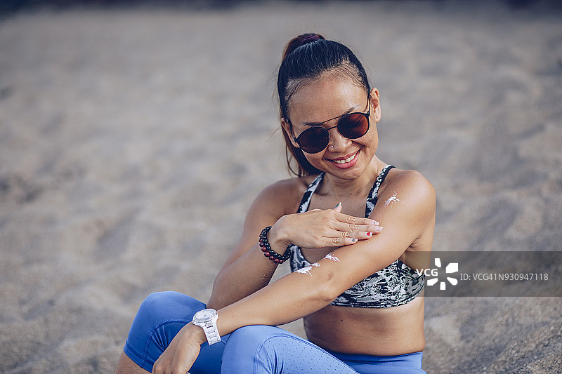 在海滩上涂抹防晒霜的运动员图片素材