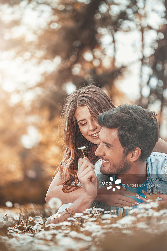 情侣躺在雏菊花田中图片素材