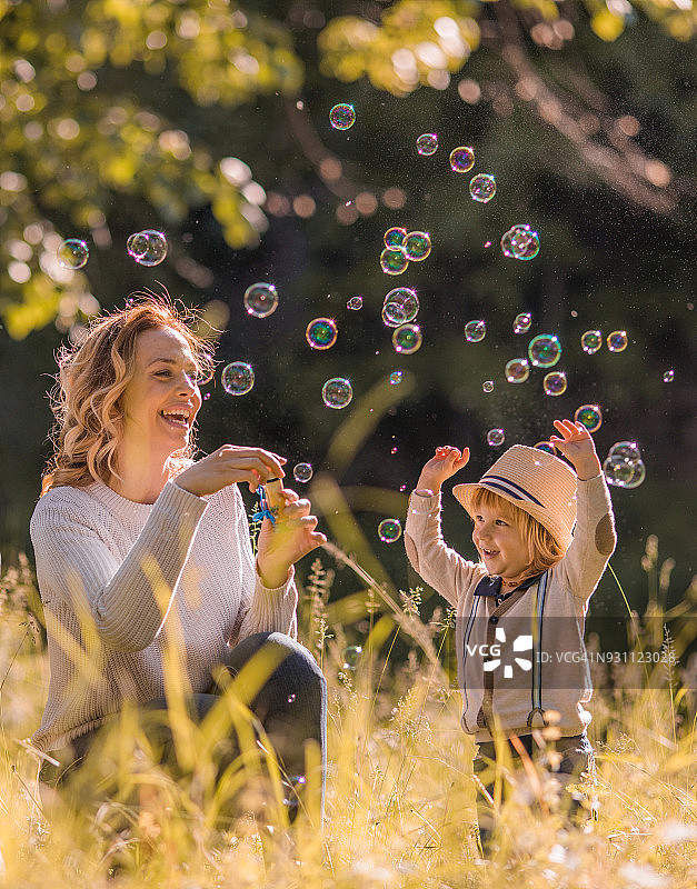 母亲和儿子在春日里吹泡泡图片素材