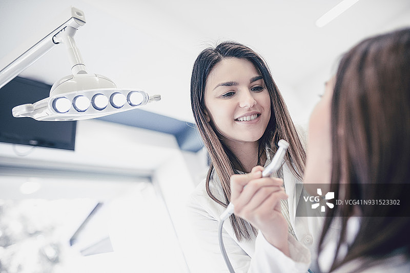 微笑的牙医在诊所检查患者的牙齿图片素材