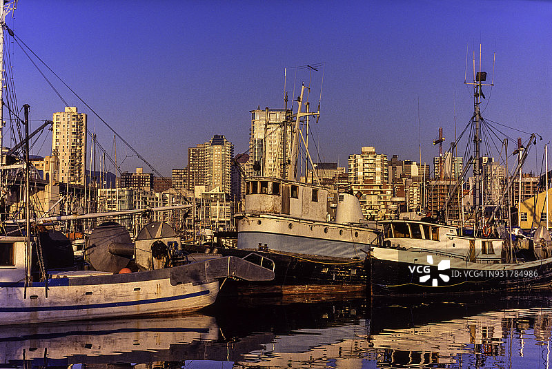 停靠在格兰维尔岛码头的渔船，背景是温哥华西区图片素材