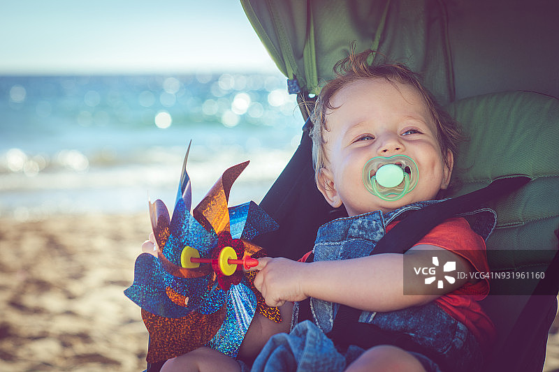 在海滩上坐在婴儿车里的男婴图片素材