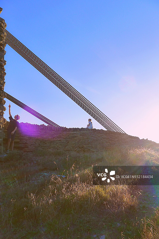 男孩和女孩坐在中奥塔哥历史悠久的吊桥上探索图片素材