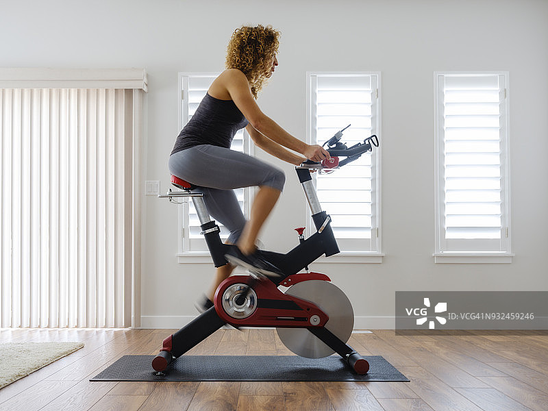 在家中动感单车上锻炼的女人图片素材