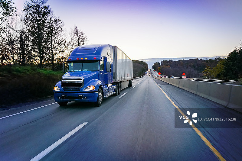 黄昏时分高速公路上的蓝色18轮半挂卡车图片素材