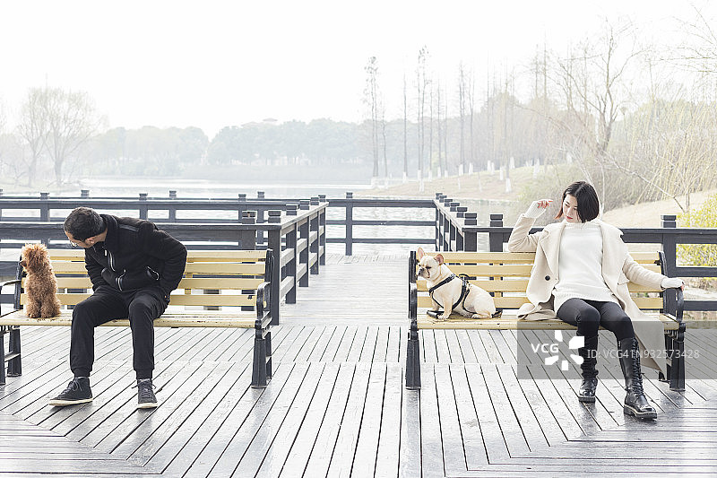 带着宠物在公园长椅上放松的年轻男女图片素材