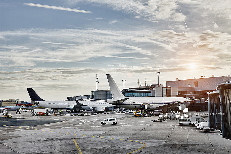 日落时停机坪上的飞机和车辆图片素材