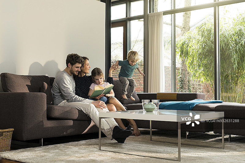 在沙发上读书的一家人，男孩在跳跃图片素材