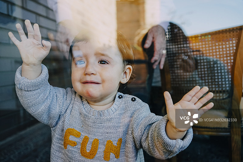 玻璃门后的哭泣女婴图片素材