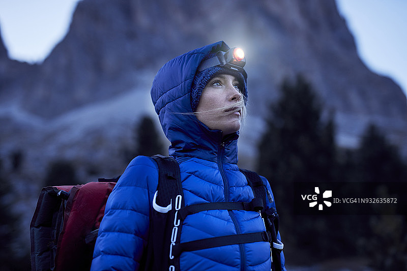 年轻女子在黄昏时分在山区戴着头灯图片素材