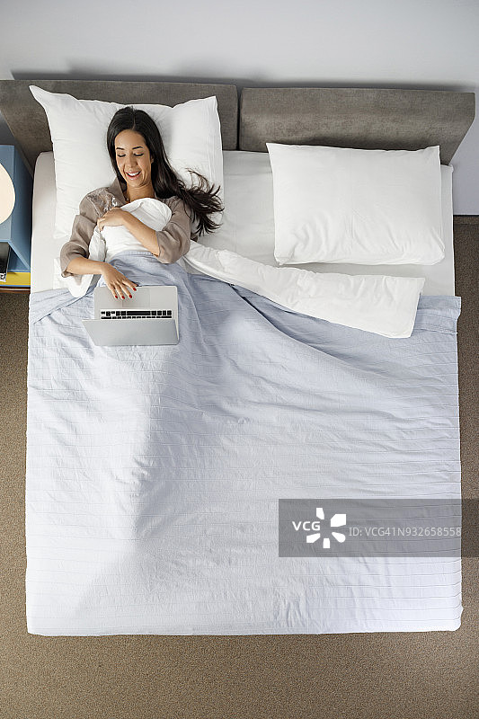 年轻女性在复古风格酒店卧室使用笔记本电脑进行网络活动图片素材