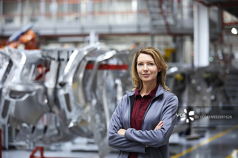 站在汽车底盘旁，双臂交叉的女工程师图片素材