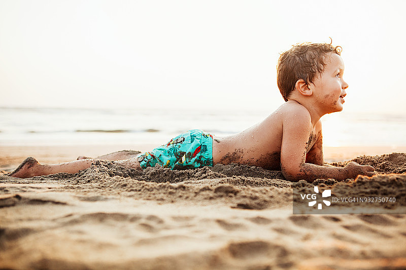 躺在海滩上快乐的小男孩的肖像图片素材