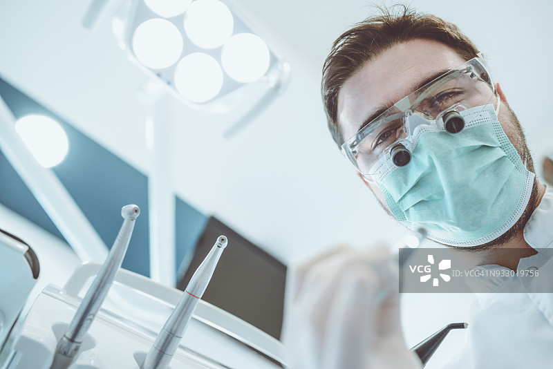 牙医戴放大镜和手术服为病人治疗图片素材