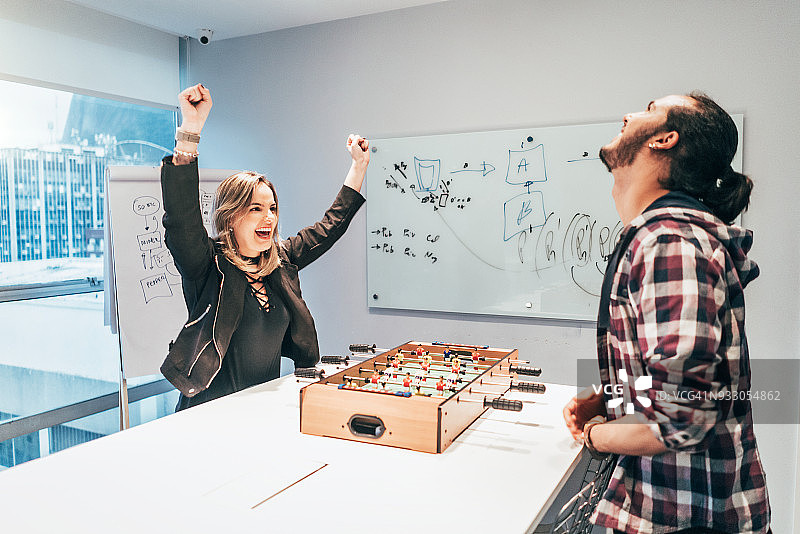 创意办公室休息期间，同事们在桌上足球上玩耍图片素材