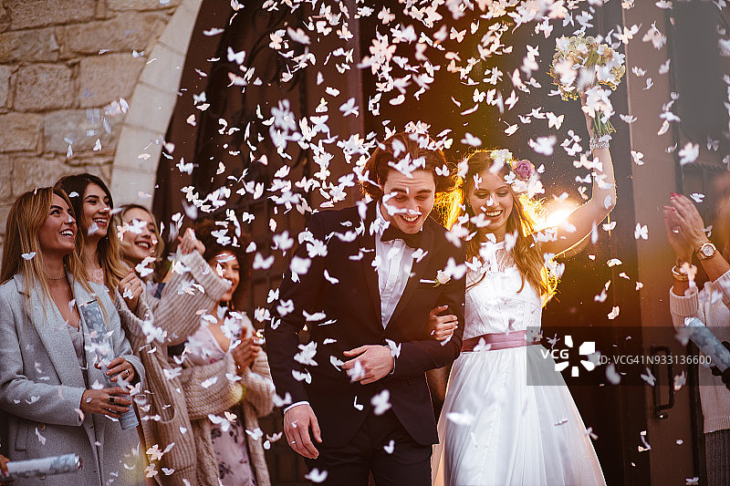 幸福的新娘和新郎离开教堂庆祝图片素材