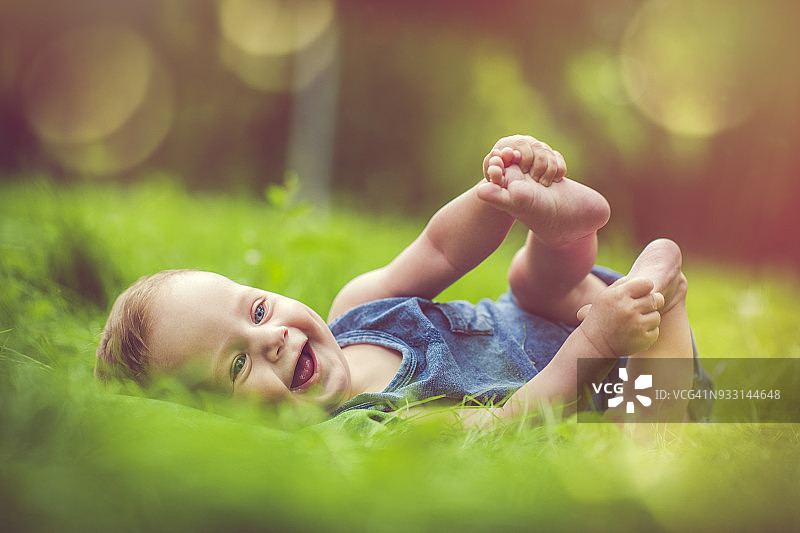 在草地上玩自己腿的可爱宝宝图片素材