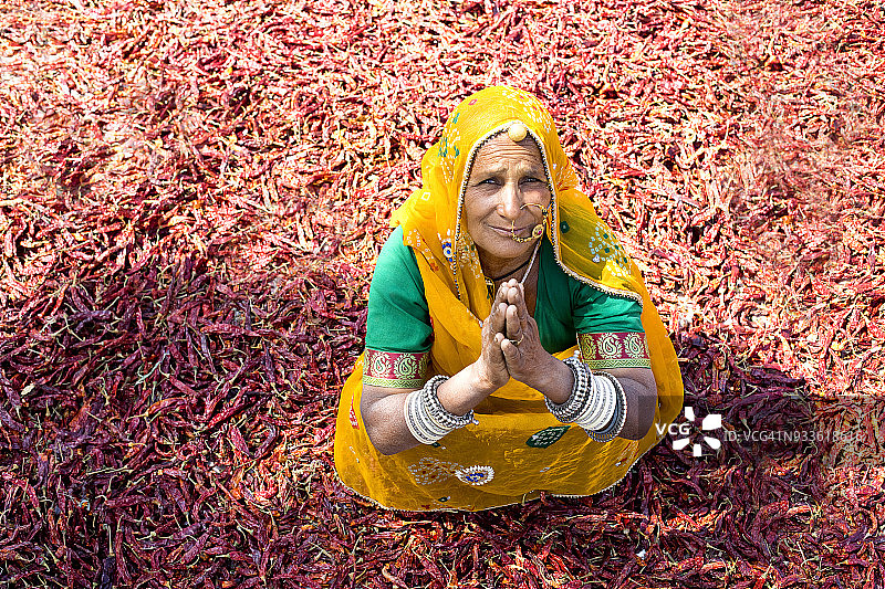 乡村妇女坐在成堆的红色干辣椒旁图片素材