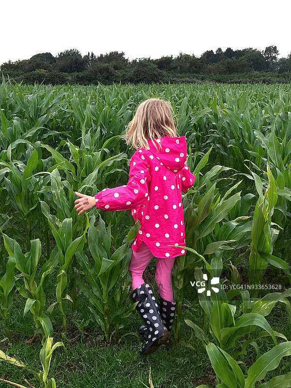 身穿波点外套的年轻女孩走在田野中图片素材