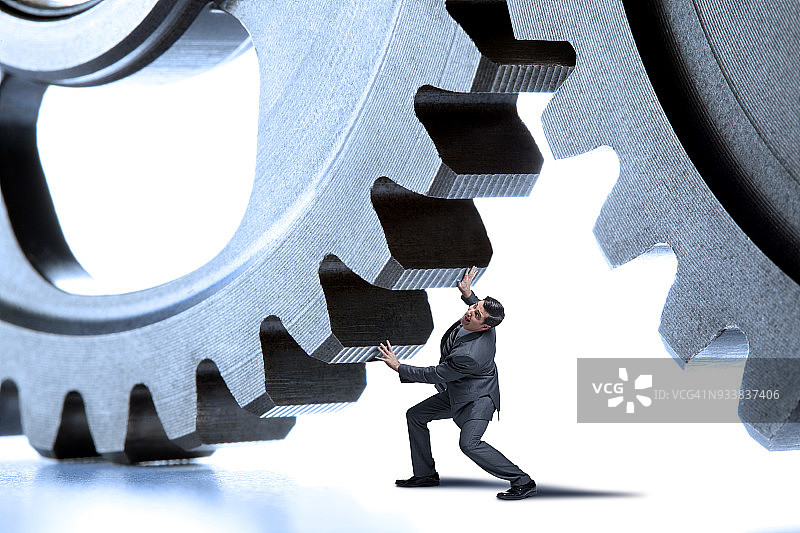 商务人士推动两个大的互锁齿轮图片素材