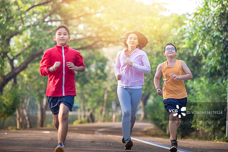 家庭运动快乐活跃的母亲和孩子在户外慢跑，在森林里跑步图片素材