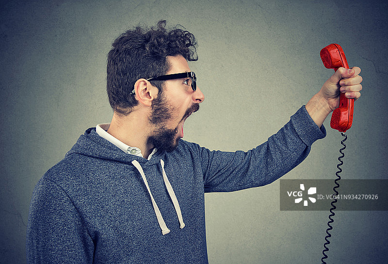愤怒的男人对着电话听筒尖叫图片素材
