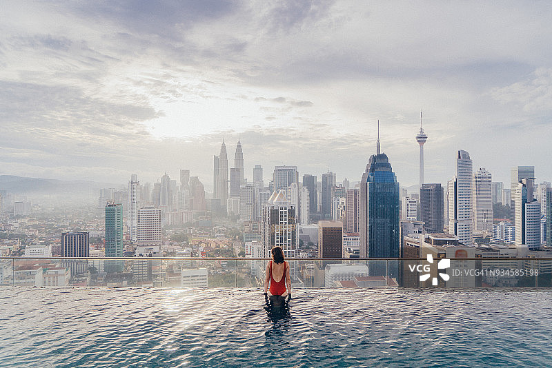 在游泳池欣赏吉隆坡美景的女人图片素材