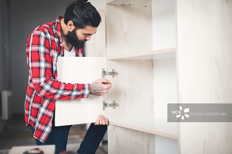 年轻男子在家具上安装门图片素材