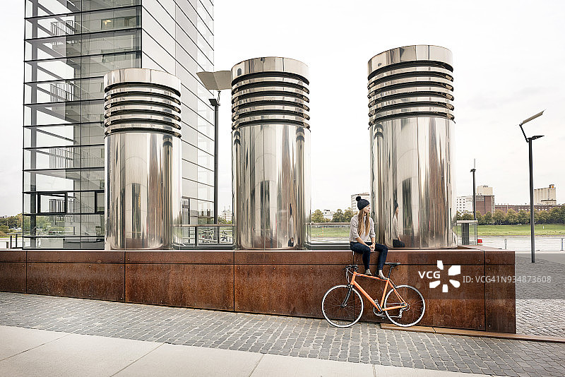 年轻女子骑自行车在城市中休息图片素材