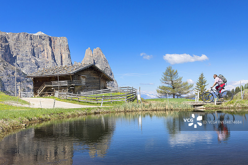 在休斯山阿尔卑斯山，春天，背景是施勒恩山的山地自行车骑行者图片素材