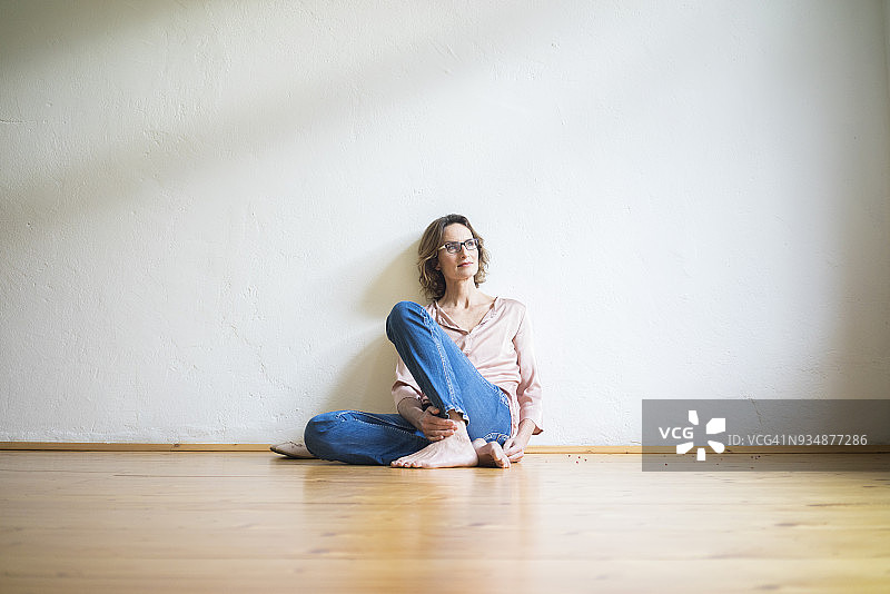 中年妇女坐在空房间的地板上思考图片素材