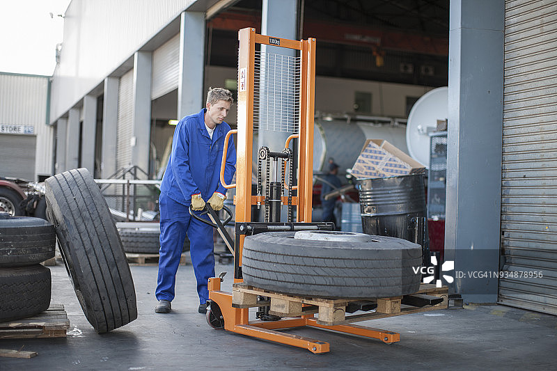 工人使用移动式叉车移动轮胎图片素材