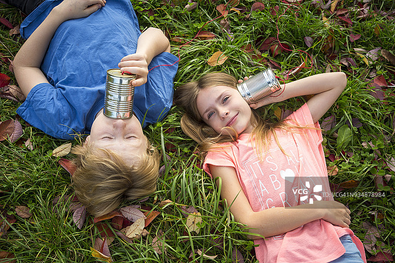 男孩和女孩在草地上用听筒电话玩耍图片素材