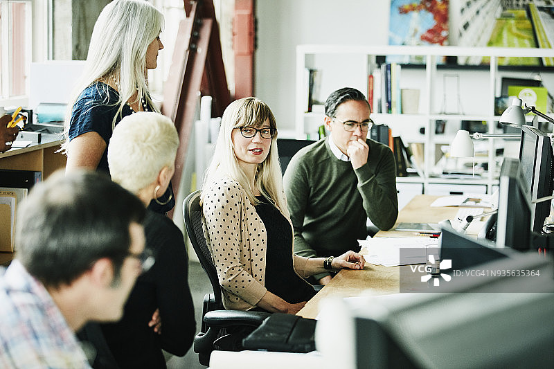 在设计办公室工作站与同事进行小组讨论的职业女性图片素材