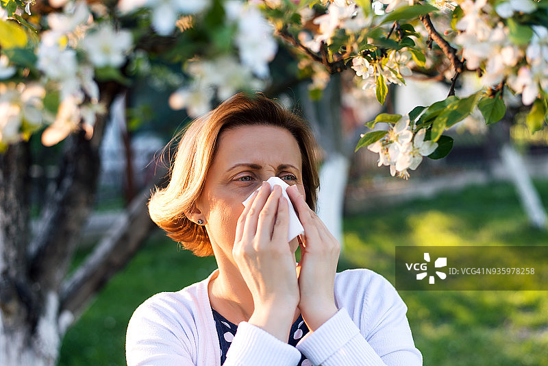 在鲜花盛开的花园里打喷嚏的女人图片素材