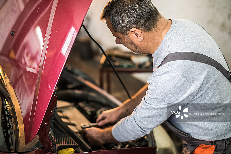 男修理工在他的汽车修理厂使用套筒扳手图片素材