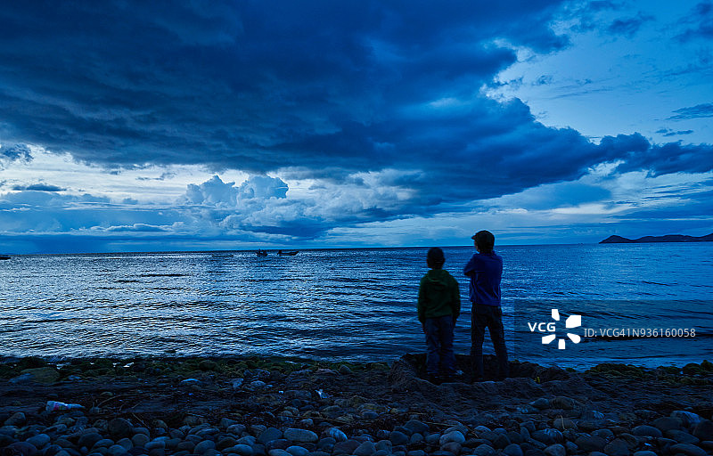 两名男孩在玻利维亚奥鲁罗科帕卡巴纳湖边欣赏风景（后视图）图片素材