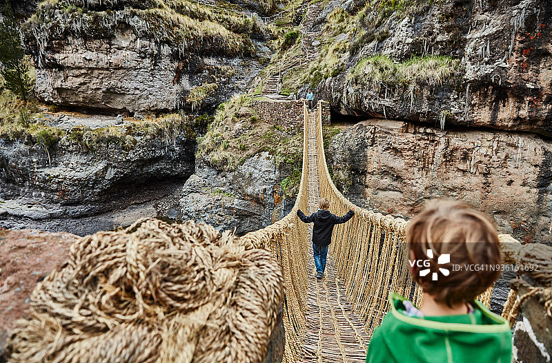 男孩、兄弟和母亲走过印加绳桥（肩上视角），秘鲁库斯科图片素材