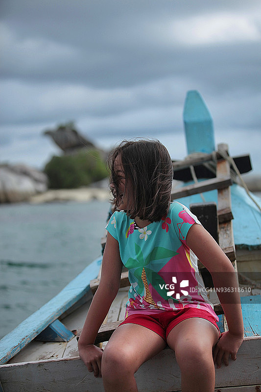 年轻女孩坐在船边欣赏海景图片素材