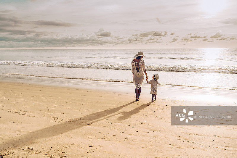 夕阳下，母子在海滩上散步交谈的背影图片素材