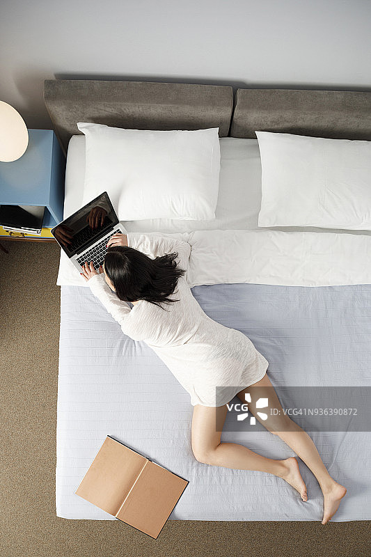 年轻女性在复古风格酒店卧室使用笔记本电脑进行网络活动图片素材